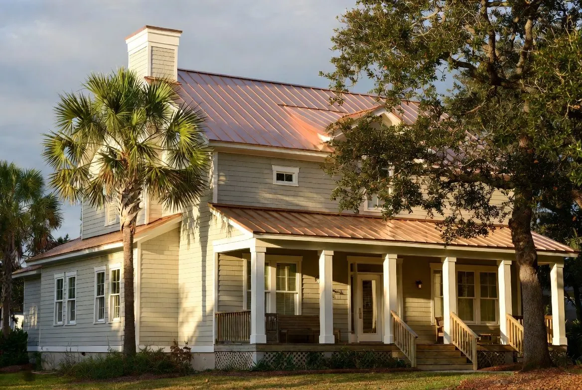 Coastal home with copper standing-seam metal roof at golden hour