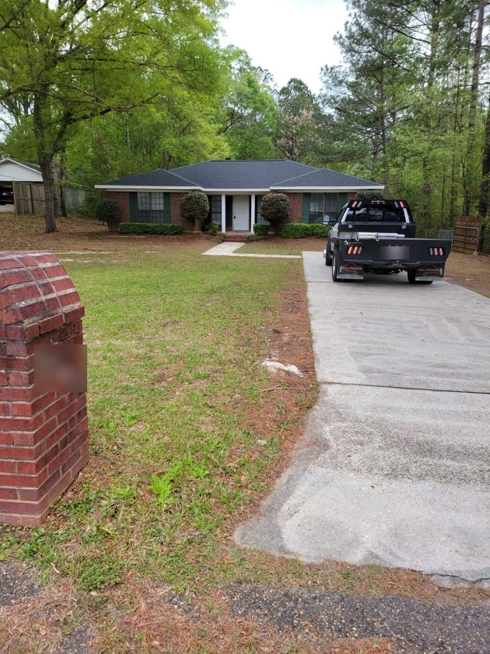 Completed architectural shingle roof on a brick ranch home with the All Phase truck in the driveway